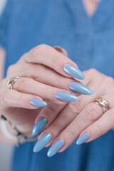 Woman's beautiful hand with long nails and bright blue manicure
