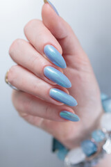 Woman's beautiful hand with long nails and light baby blue manicure	