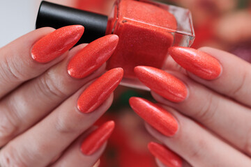 Woman hand with long nails and light orange coral neon manicure