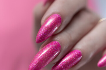 Female hand with long nails and a bottle bright neon pink fuchsia color nail polish