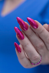 Female hand with long nails and a bottle bright neon pink red color nail polish