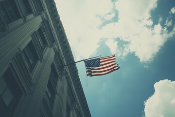 An American flag waves proudly against a bright blue sky, its vibrant colors a testament to freedom and patriotism, seen from the low angle of a towering, classical building.