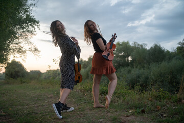 Two happy women friends violinists portrait outdoor in the evening