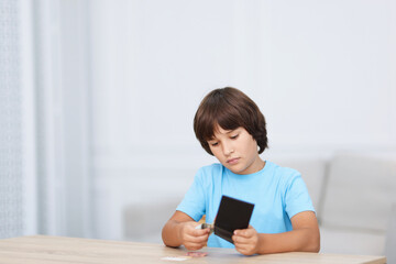 Naklejka premium Boy with pocket money at wooden table indoors. Space for text