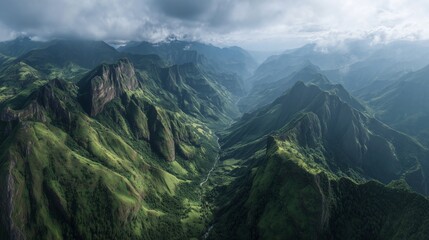 Naklejka premium Green mountains rise sharply, with the green slopes cascading into valleys below. Shadows from clouds cover the green terrain, blending into the mountainous landscape.