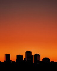 Silhouetted City Skyline Against Fiery Orange Sunset Sky, Dramatic Evening Scene.