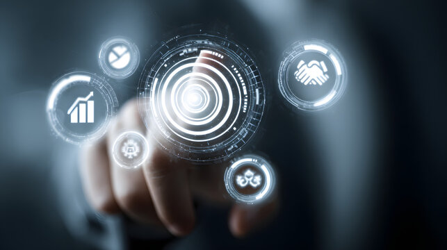 A person's finger touches a glowing digital interface depicting business icons, surrounded by radiating light, suggesting technology and data analytics with the backdrop of a dark environment.