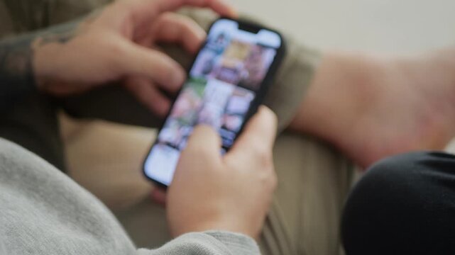 Man using his smartphone to scroll through an Instagram feed, browsing posts and videos. Close-up captures social media interaction, digital engagement, and modern mobile lifestyle.