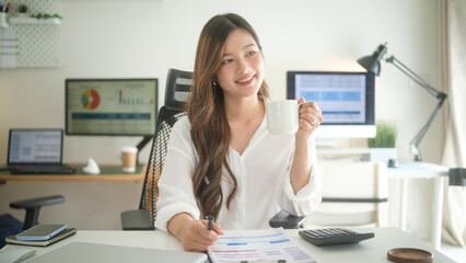 Young businesswoman holding a coffee cup and smiling during work.