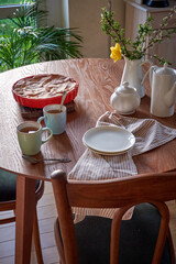 Traditional apple pie on a wooden plate on a light culinary background. Charlotte pie on a platter in closeup. Delicious homemade cakes on the kitchen table