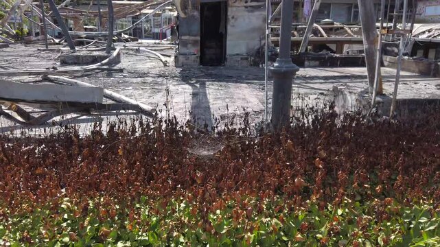 Destruction aftermath of a recent fire incident in a construction site with scattered debris and damaged structures