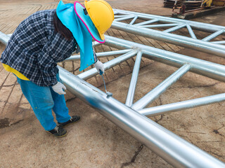 Worker wearing protective gear painting galvanized steel structure at construction site to prevent...