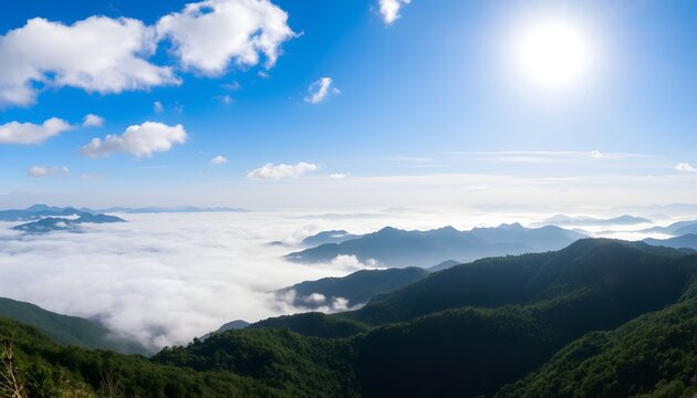 A panoramic view of a majestic mountain range above a sea of clouds under a bright blue sky with a radiant sun.