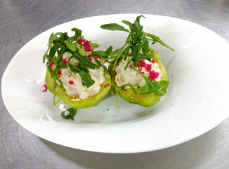 A sophisticated appetizer: avocado halves filled with a creamy, creamy seafood filling, garnished with fresh arugula and sprinkled with vibrant pink caviar.