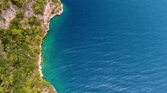 aerial footage captures the stunning natural beauty of Gokova Bay G&ouml;kova K&ouml;rfezi in Turkey. The vibrant turquoise waters of the Aegean Sea meet a rugged coastline adorned with lush green forests, crea