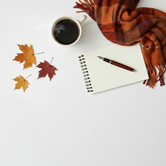 Minimalist Soft Autumn Feminine White Desk Wide Flatlay with notepad and blank negative space with fallen orange red leaves