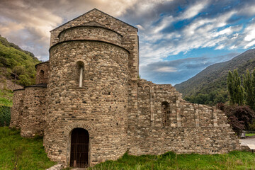 The ancient Romanesque architecture of the historic Sant Serni de Tavèrnoles monastery under a dramatic, stormy sky in the Catalan Pyrenees