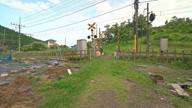 A Quiet Railroad Crossing on a Countryside Footpath in Japan with Green Hills in the Background