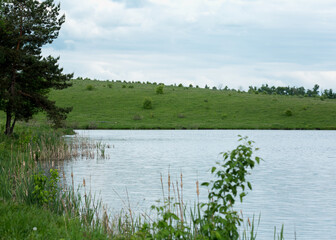Serene Lake Scene with Lush Green Hills and Cloudy Sky
