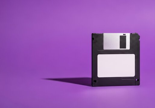 retro 3.5-inch floppy disk with blank white label on vibrant purple background. vintage technology and nostalgia concept. web design, banner with copyspace.