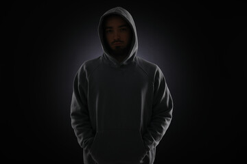 Criminal man in hood on dark background