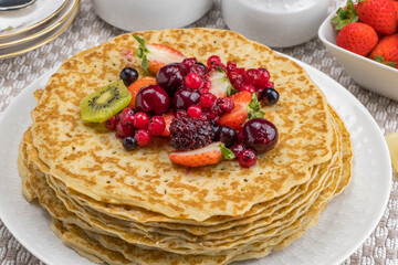 Crepes con kiwi, fresas y frutos rojos, sobre una mesa