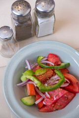 Plato de aperitivo con ensalada, pimenteros y salero en un restaurante.