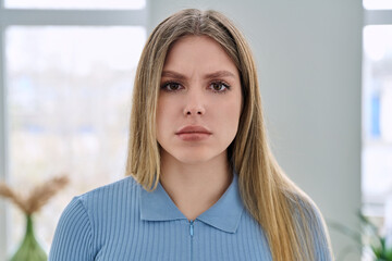 Headshot portrait of young serious woman looking at camera