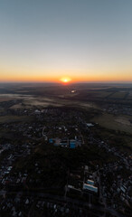 Sun shining on horizon above countryside with fields and villages