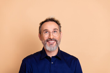 Obraz premium Successful mature male with stylish beard and glasses in formal blue shirt smiling against beige office background