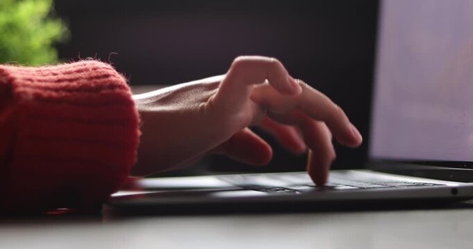 Hand of woman using laptop computer to work, typing at home and scrolling, while sitting on table workplace at night, Close-up of young women hand	