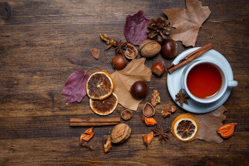 Aerial view of a cup of white tea with cinnamon on a table with nuts and autumn leaves, horizontal, with copy space