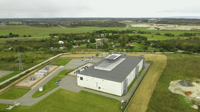 Aerial drone revealing shot of a data center in sunny countryside for AI, Algorithms, data, Intelligent Systems, cryptography and security and quantum computing, Server space.