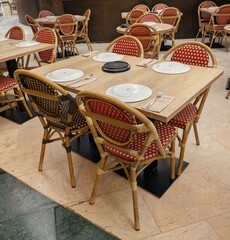 Mesa con platos y sillas de madera en terraza en un restaurante de un centro comercial