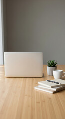 Laptop, plant, and coffee cup on a wooden desk against a gray wall