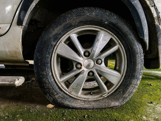 Close-up of a flat car tire with dirty rim, symbolizing vehicle breakdown, maintenance issues, road safety risks, and emergency situations related to car tire damage.