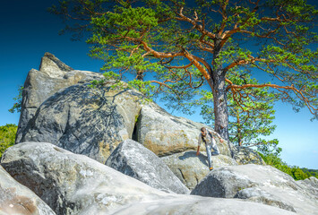 Man climbing rocky mountain with backpack, hiking adventure and outdoor exploration in summer nature