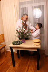 A man in Ukrainian embroidery and his son decorate a Christmas tree.