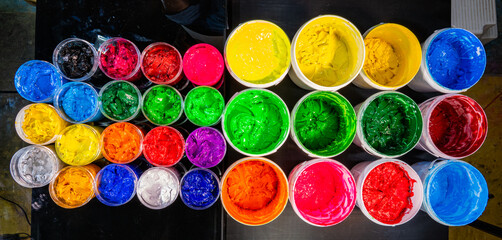 Colorful Ink for Screen Printing Factories
Inside a busy Tee shirt factory plastisol inks in multiple tones bright and dark are neatly arranged for industrial use. Workers use handmade tools handles