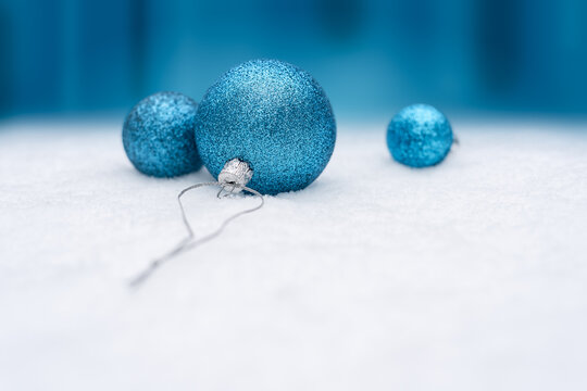 Blue Christmas Baubles On Snow With Festive Blue Background And Copy Space