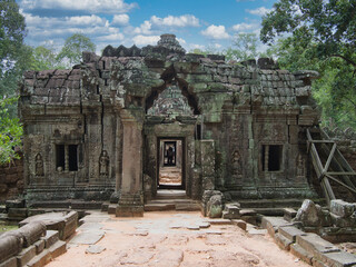 Crumbling Angkor Temple Gate - A weathered temple gate at Angkor, surrounded by dense jungle, showing a passage into the ancient and mysterious structure.