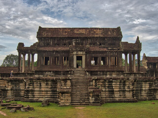 The Library of Angkor Wat - The impressive ancient library building at Angkor Wat, with its classical Khmer architecture and detailed carvings, under a dramatic cloudy sky.