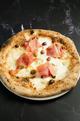Artisan pizza with prosciutto and olives