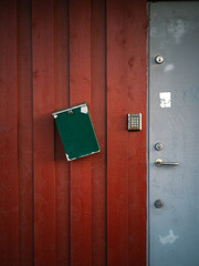 Red wall with grey steel door, key code and green mailbox hanging crooked 