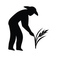 Silhouette of a farmer wearing a hat tending to a stalk of wheat in a field