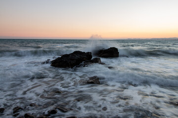 Evocative Long Exposure of Ocean Waves Crashing Against Rugged Rocks During Twilight