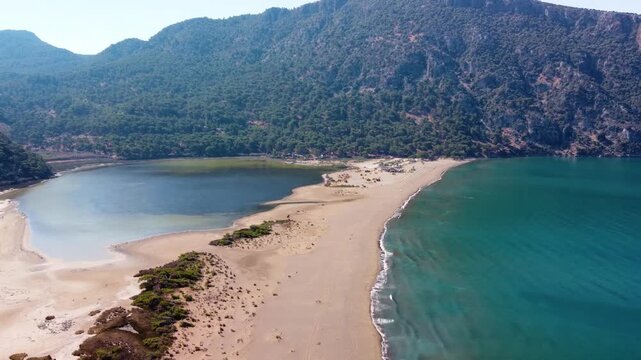 aerial perspective showcasing the stunning natural beauty of Iztuzu Beach in Dalyan, Turkey. This unique landscape features a narrow sandy spit separating the freshwater Dalyan River delta from the tu