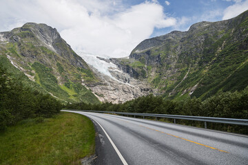 Winding Road Through a Majestic Glacial Mountain Valley Under a Cloudy Sky