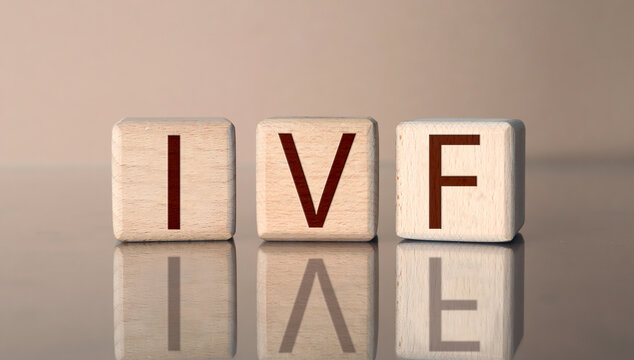 In vitro fertilization. Wooden cubes with abbreviation IVF on pale brown background. Banner design