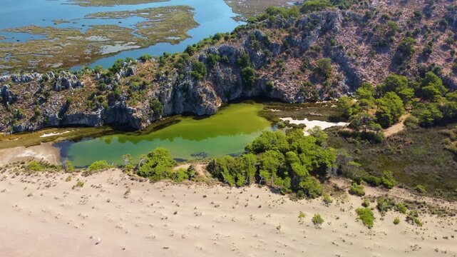 An aerial drone shot captures the stunning natural beauty of Iztuzu Beach in Dalyan, Turkey. This unique sandy spit acts as a vital natural barrier separating the freshwater Dalyan River delta from th